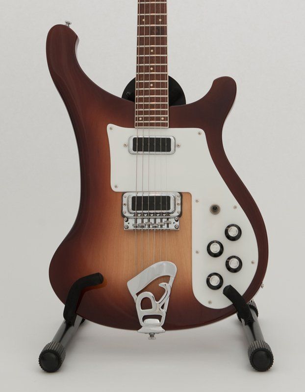A brown and white electric guitar is sitting on a stand