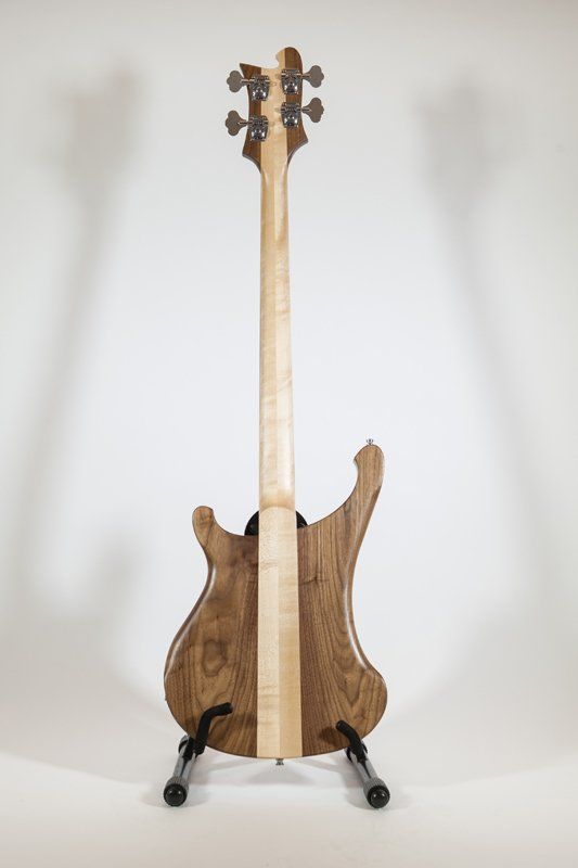 The back of a bass guitar is shown on a stand.