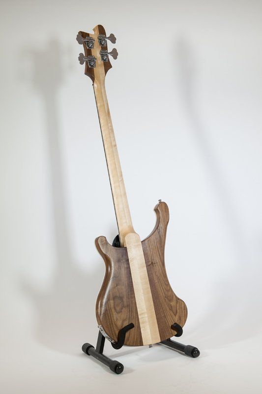 A bass guitar is sitting on a stand on a white surface.