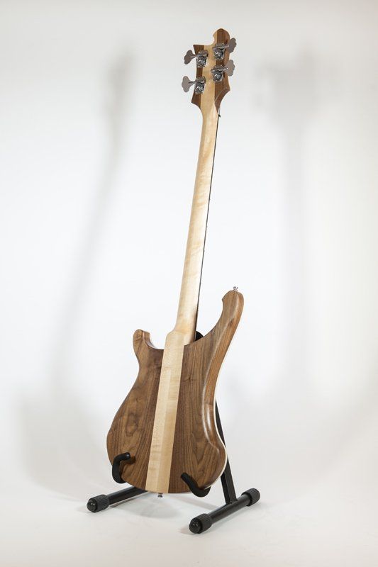 A wooden bass guitar is sitting on a stand.