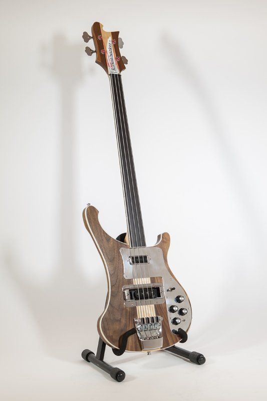A bass guitar is sitting on a stand on a white background.