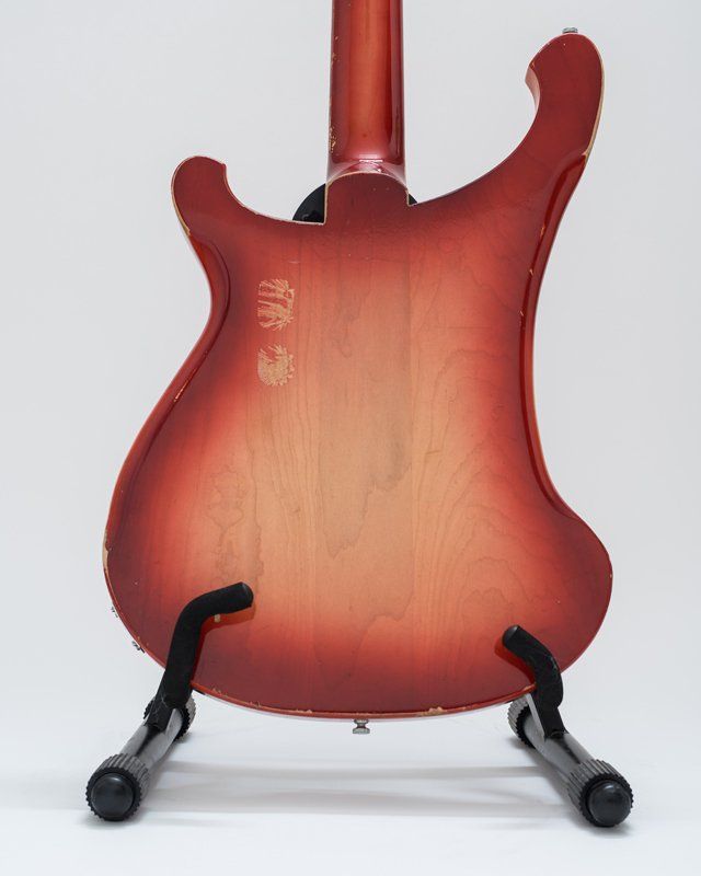 A red guitar is sitting on a guitar stand