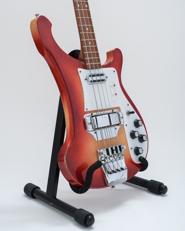 A red guitar is sitting on a black stand