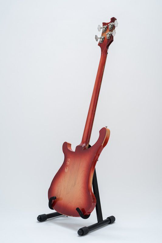 A red electric guitar is sitting on a stand.