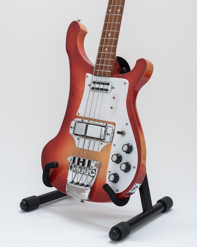 A red and white electric guitar is sitting on a stand