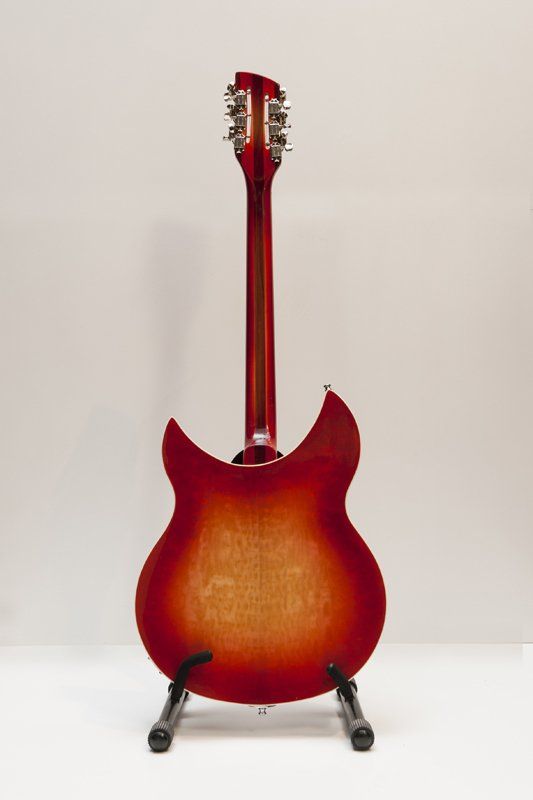 The back of a red electric guitar is sitting on a stand.