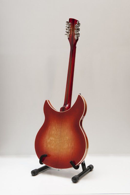 A red electric guitar is sitting on a stand.