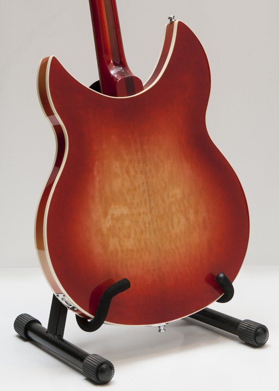 A red guitar is sitting on a black stand