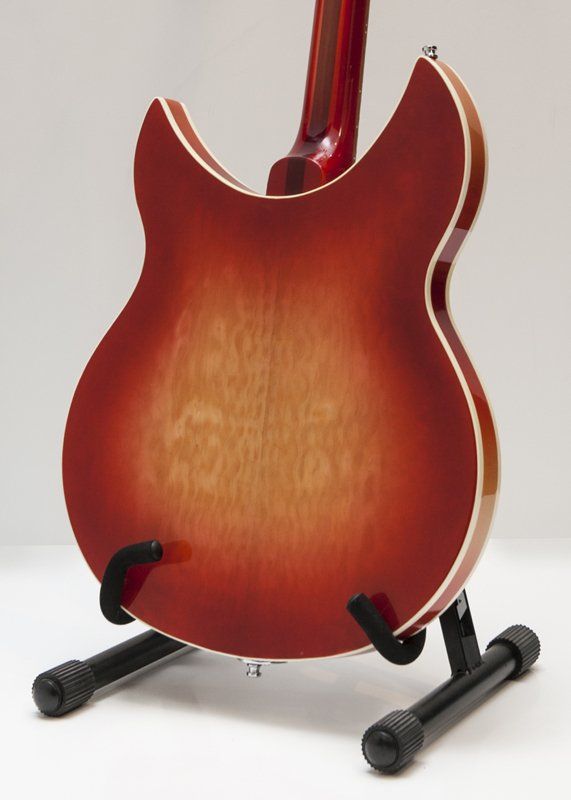 A red guitar is sitting on a black stand