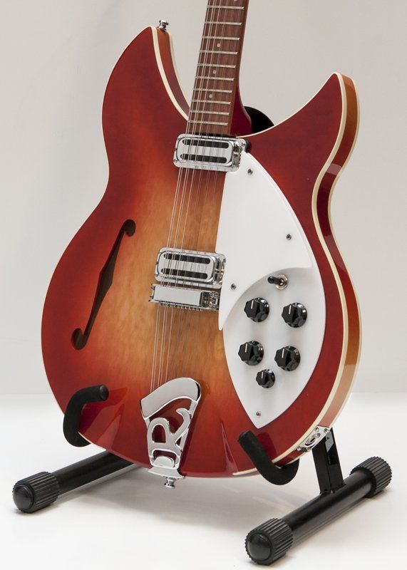 A red and white guitar is sitting on a stand