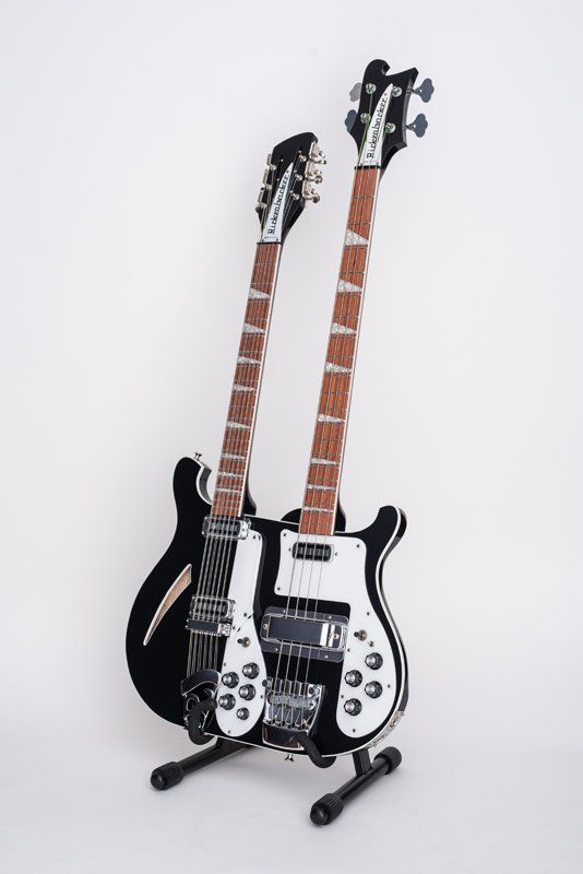 Two guitars are sitting on top of each other on a stand.