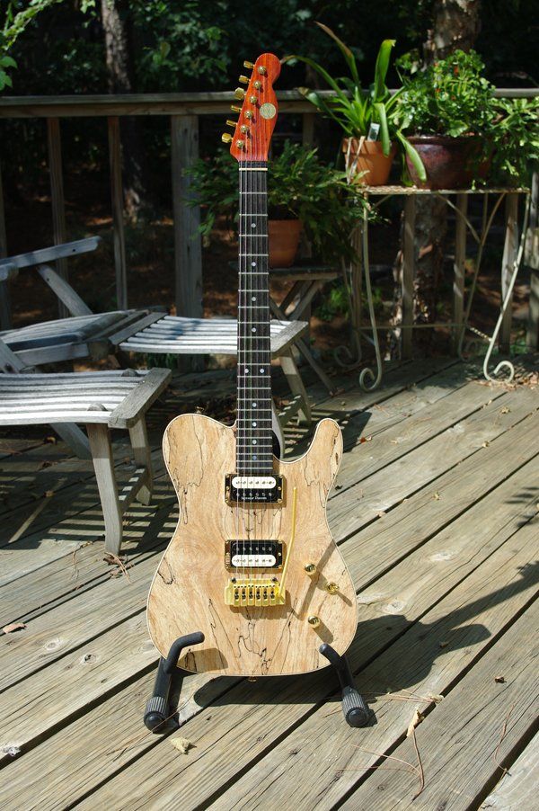 A wooden guitar is sitting on a wooden deck.