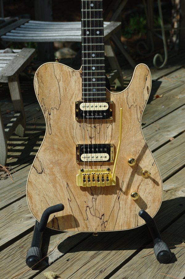 A guitar is sitting on a stand on a wooden deck