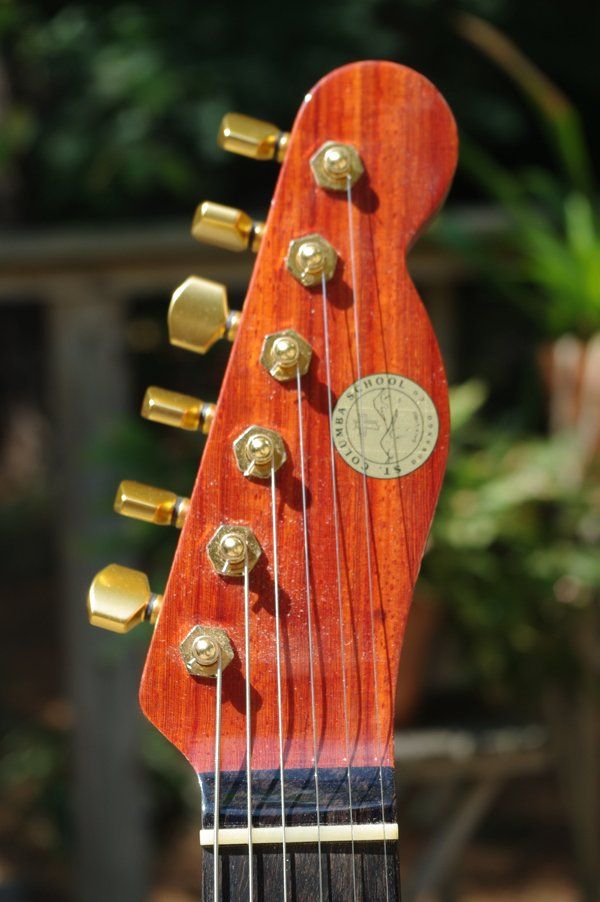 A close up of a guitar headstock with gold knobs