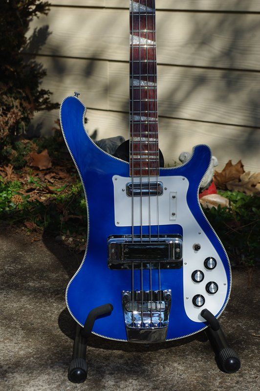 A blue and white bass guitar is sitting on a stand
