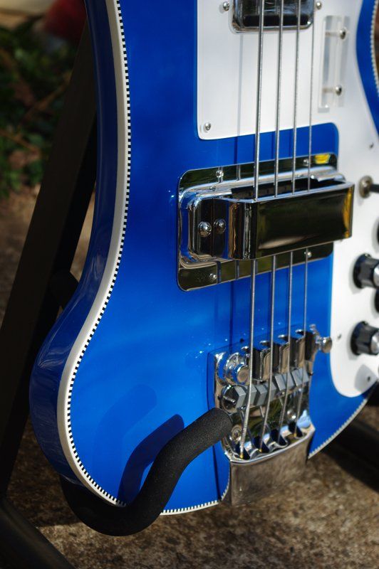 A blue and white bass guitar is sitting on a stand