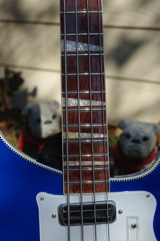 A blue bass guitar with two teddy bears in the background