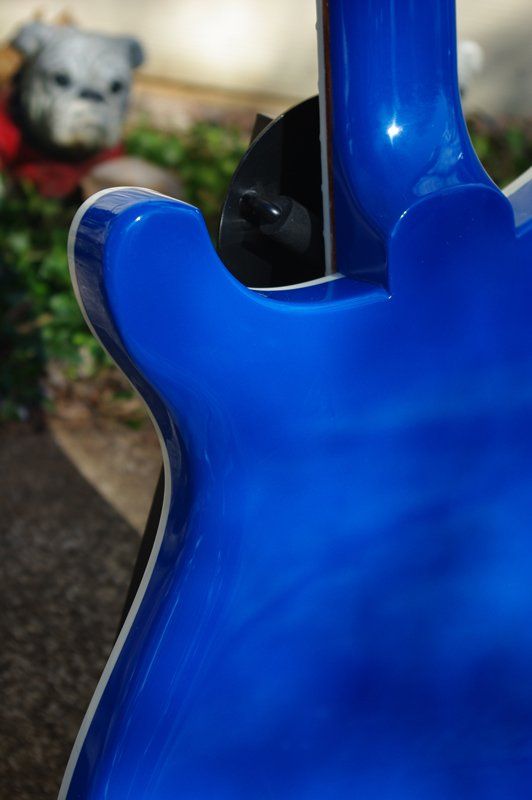 The back of a blue electric guitar with a stuffed animal in the background.