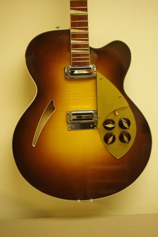 A brown and yellow guitar is hanging on a wall