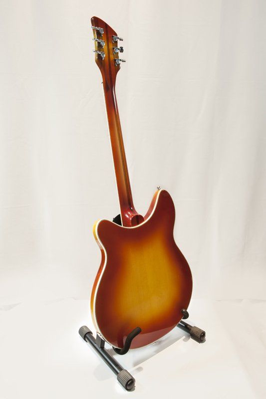 A guitar is sitting on a stand on a white background.