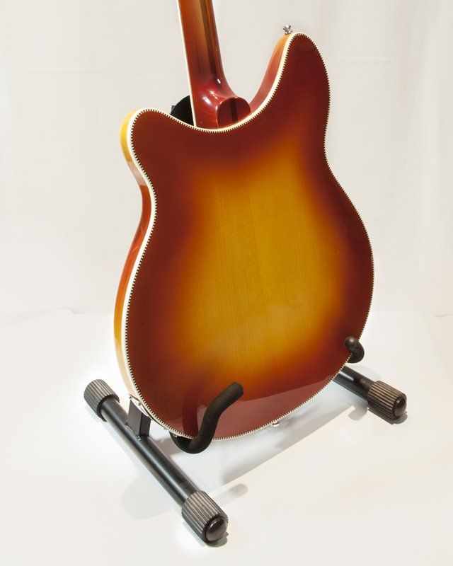 The back of a guitar is shown on a stand
