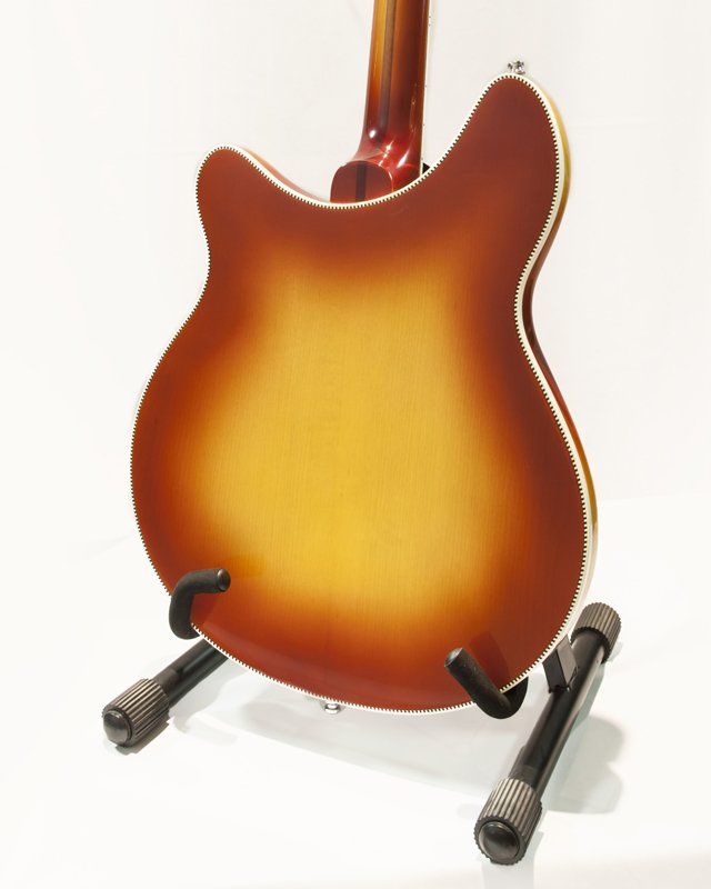 The back of a guitar is shown on a stand