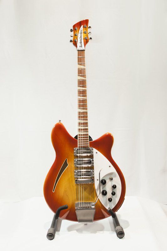 A guitar is sitting on a stand on a white surface.