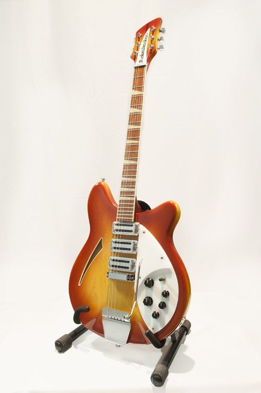 A red and yellow electric guitar is sitting on a stand.