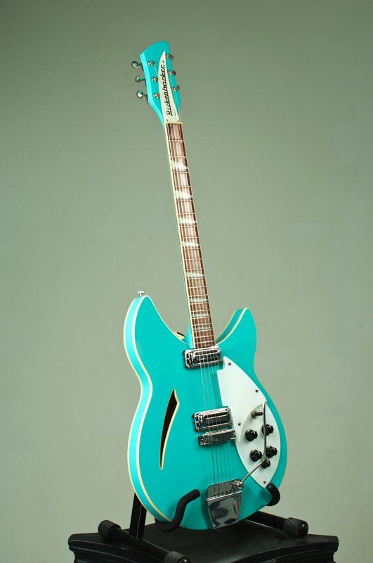 A turquoise electric guitar is sitting on a stand.