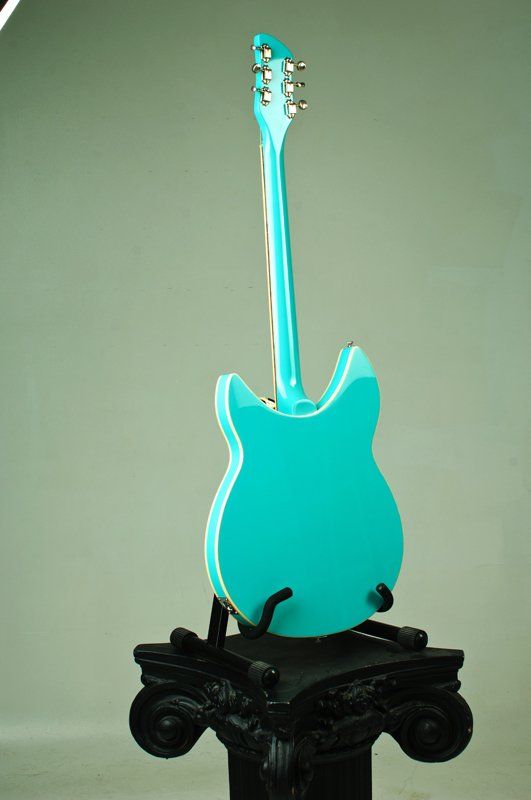 A blue guitar is sitting on top of a black pedestal