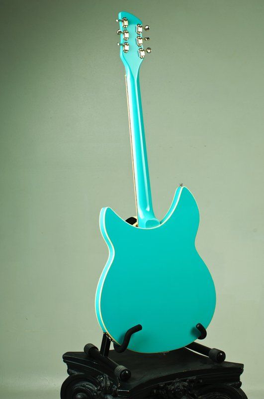 A turquoise electric guitar is sitting on a black stand.