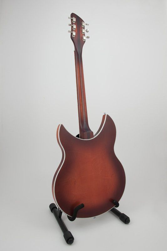 A guitar is sitting on a stand on a white surface.
