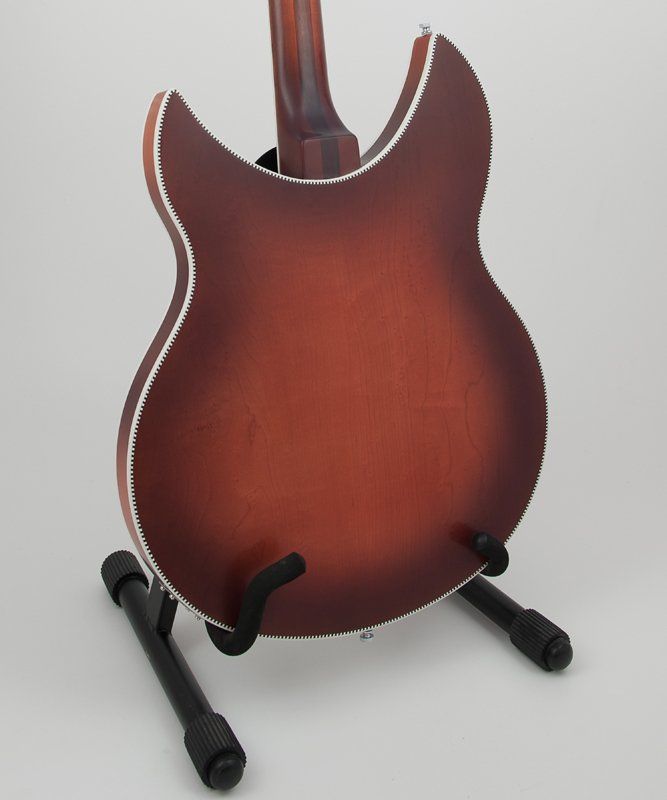 The back of a guitar is shown on a stand