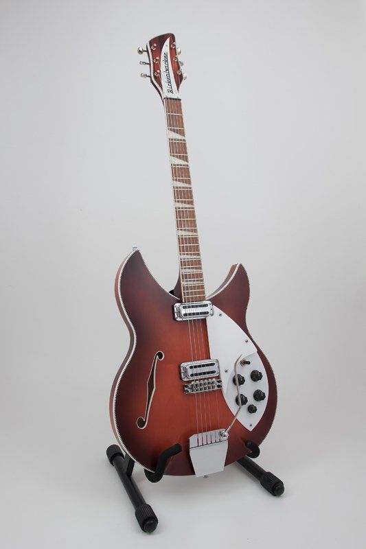 A guitar is sitting on a stand on a white surface.