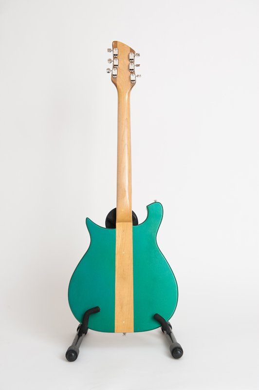 The back of a green electric guitar on a stand.