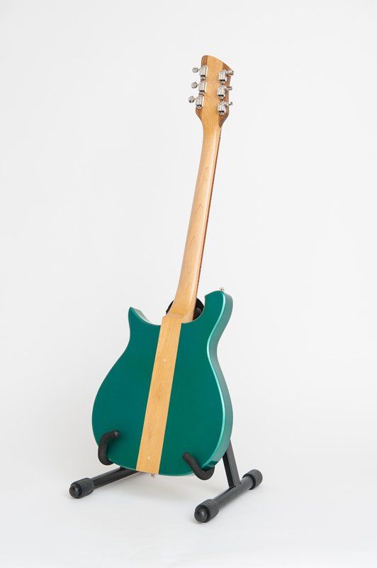 A green guitar is sitting on a stand on a white background