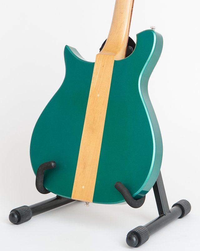 A green guitar is sitting on a black stand