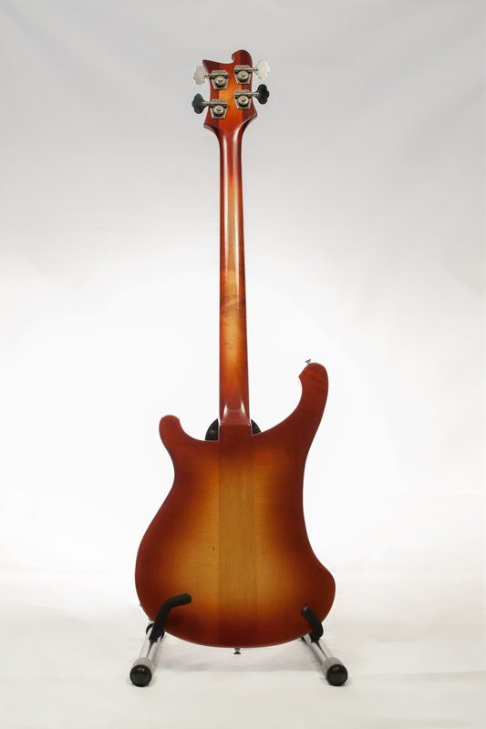 A bass guitar is sitting on a stand on a white background.