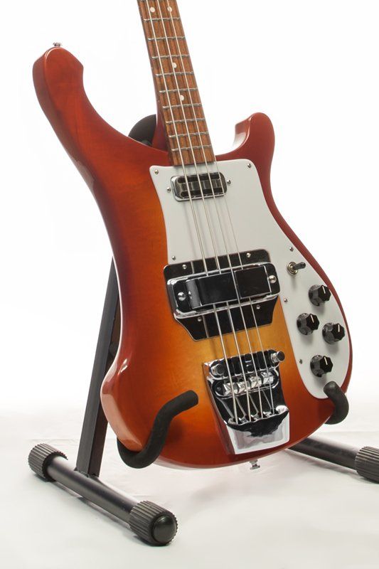 A bass guitar is sitting on a stand on a white background