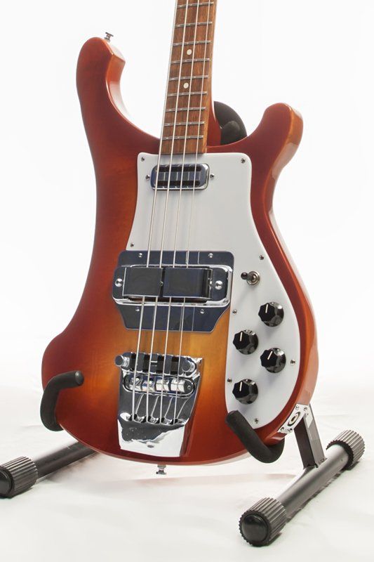 A bass guitar is sitting on a stand on a white background