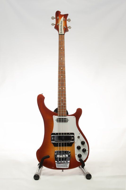 A bass guitar is sitting on a stand on a white background