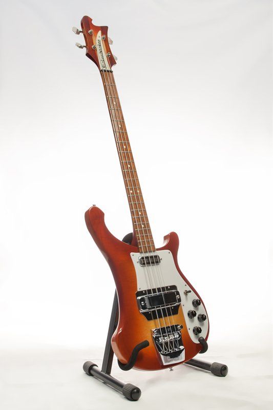 A bass guitar is sitting on a stand on a white background
