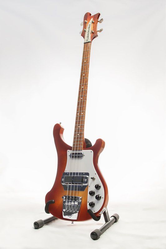 A bass guitar is sitting on a stand on a white background.