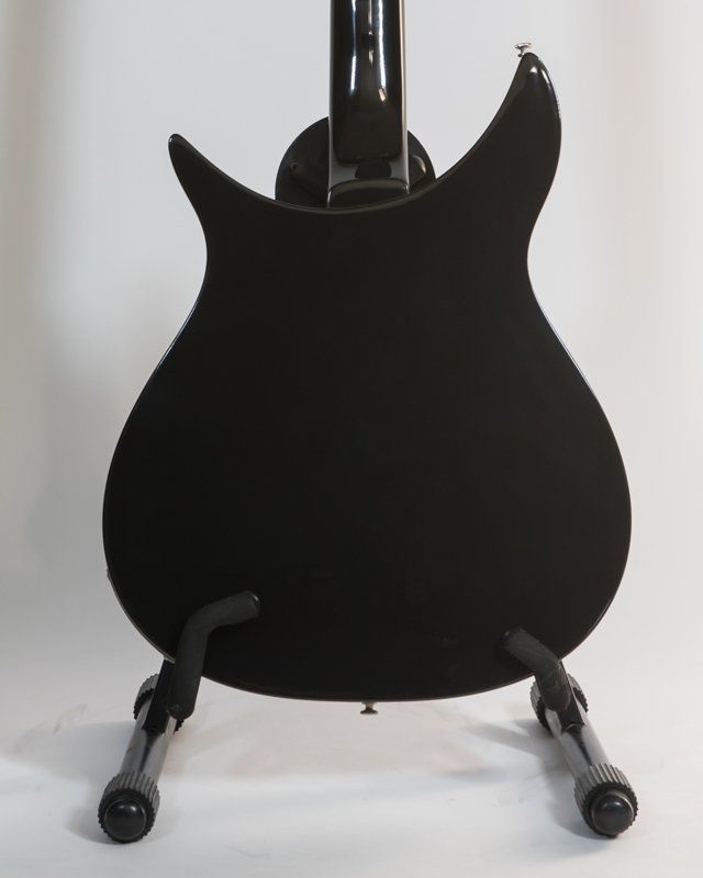 The back of a black guitar is shown on a stand