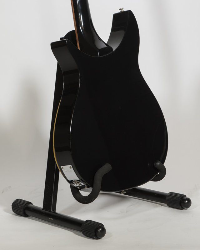 A black guitar is sitting on a black stand