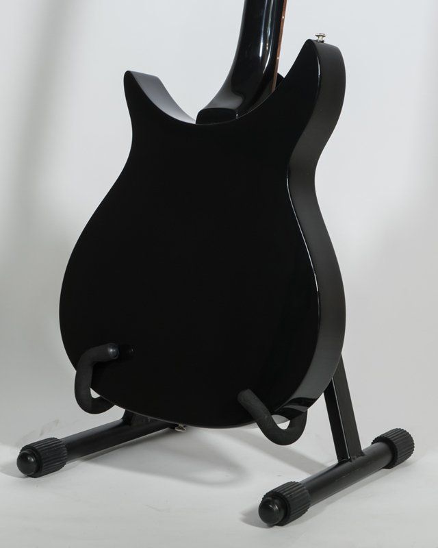 A black guitar is sitting on a black stand