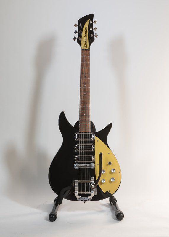 A black and yellow electric guitar is sitting on a stand