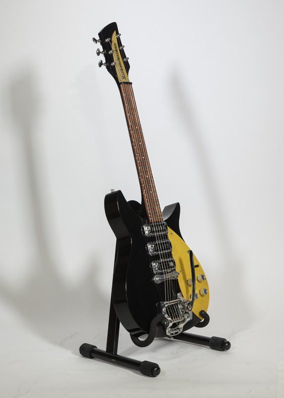 A black and yellow electric guitar on a stand