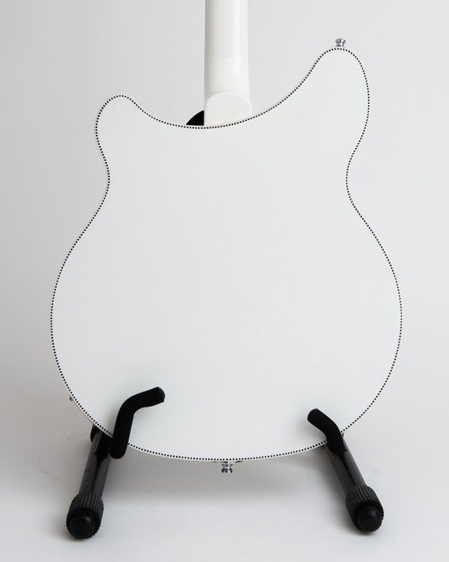 A white guitar is sitting on a black stand