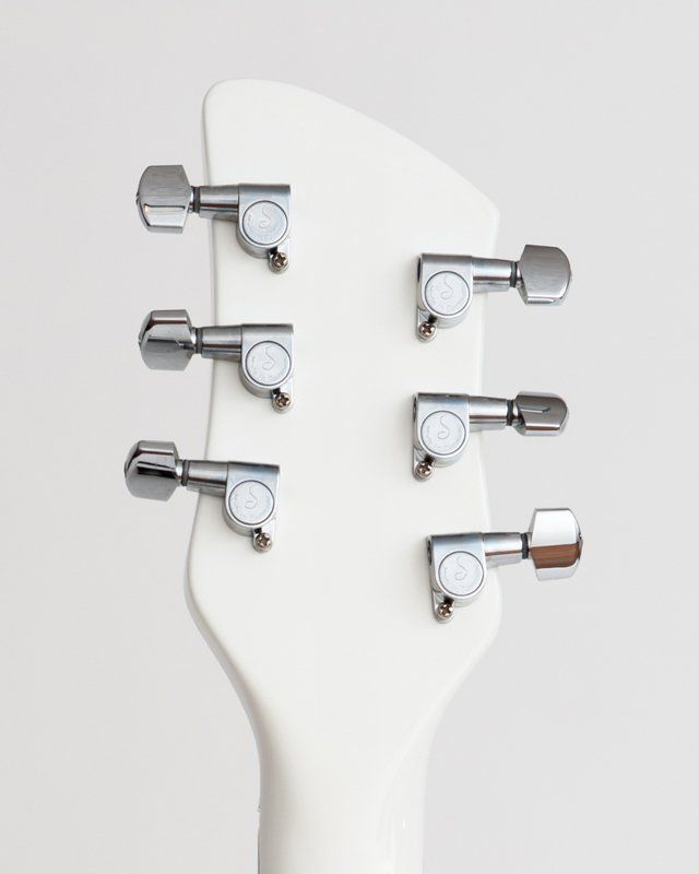 A close up of a white guitar headstock with chrome tuners